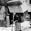 Diese Frau transportiert Körbe mit Spielwaren trotz ihres Alters zu einem äußerst niedrigen Lohn (etwa 1925).